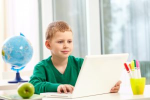 schoolboy with laptop on his desk